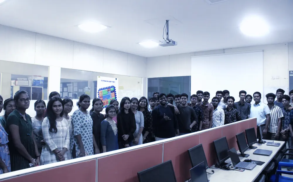 A group standing together in a computer lab lined with workstations at a KaizenSpark Tech session.